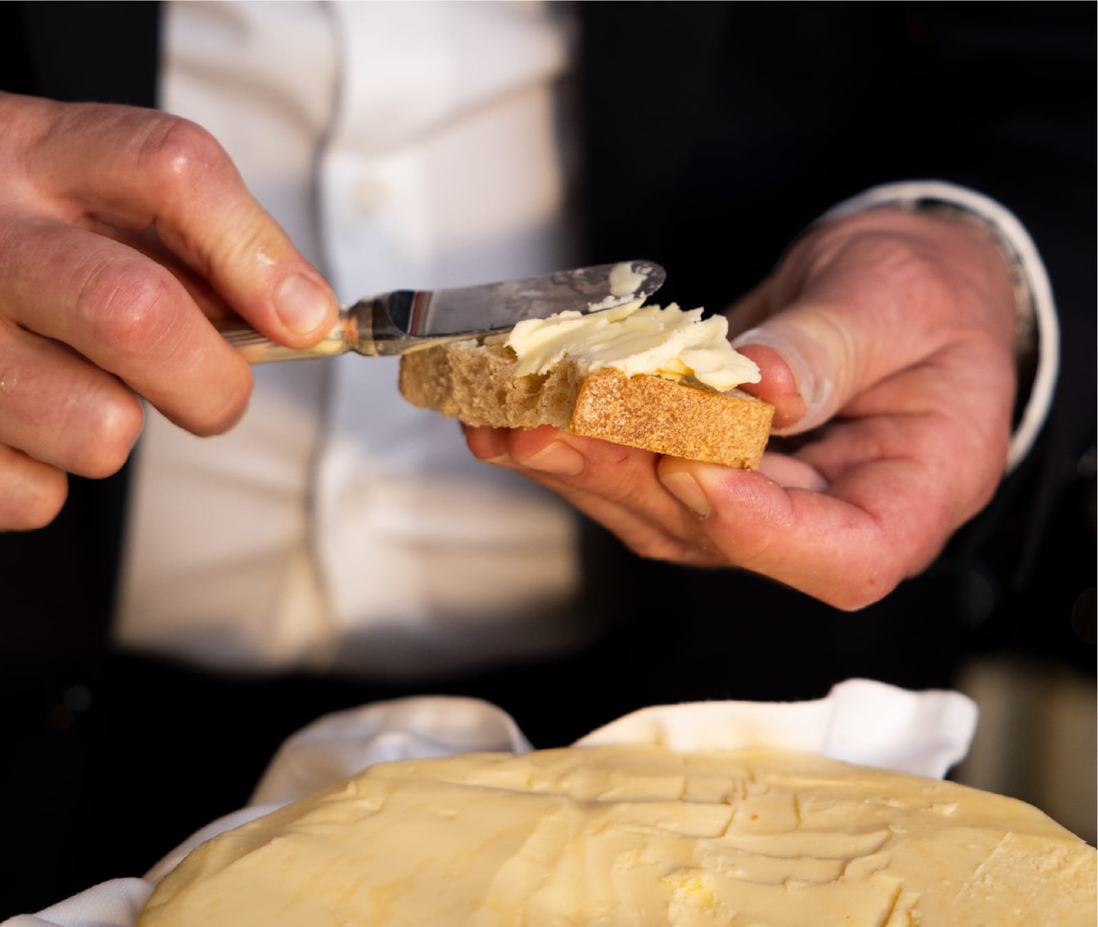 Mani che spalmano burro su una fetta di pane durante il servizio