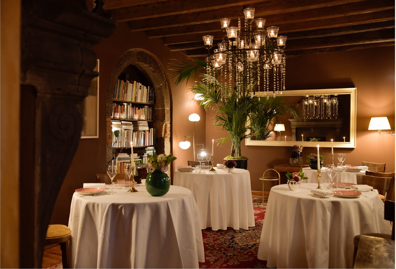 Sala dell’Osteria allestita con tavoli rotondi sotto il lampadario di cristalli