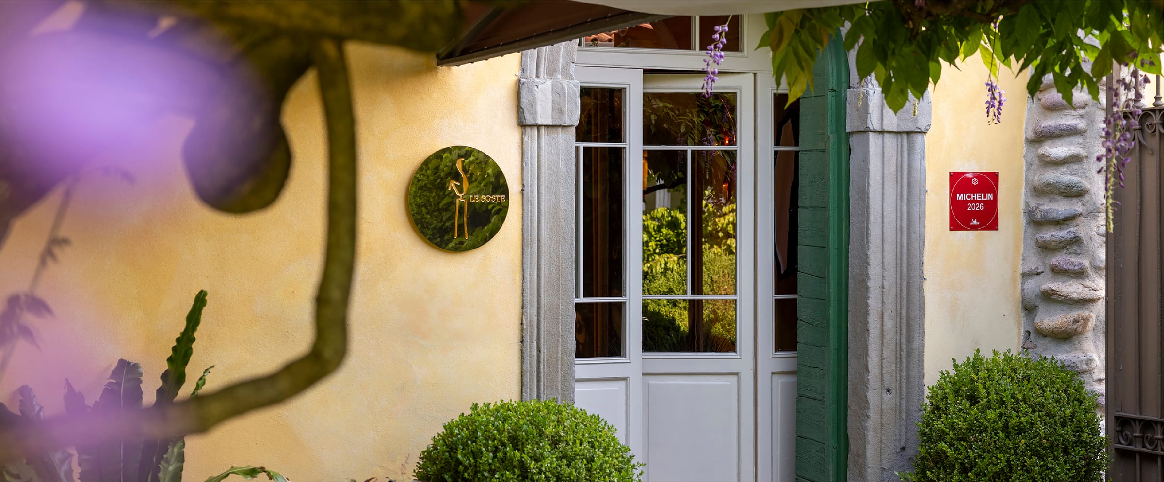 L’ingresso dell’Osteria della Brughiera tra glicini e piante fiorite