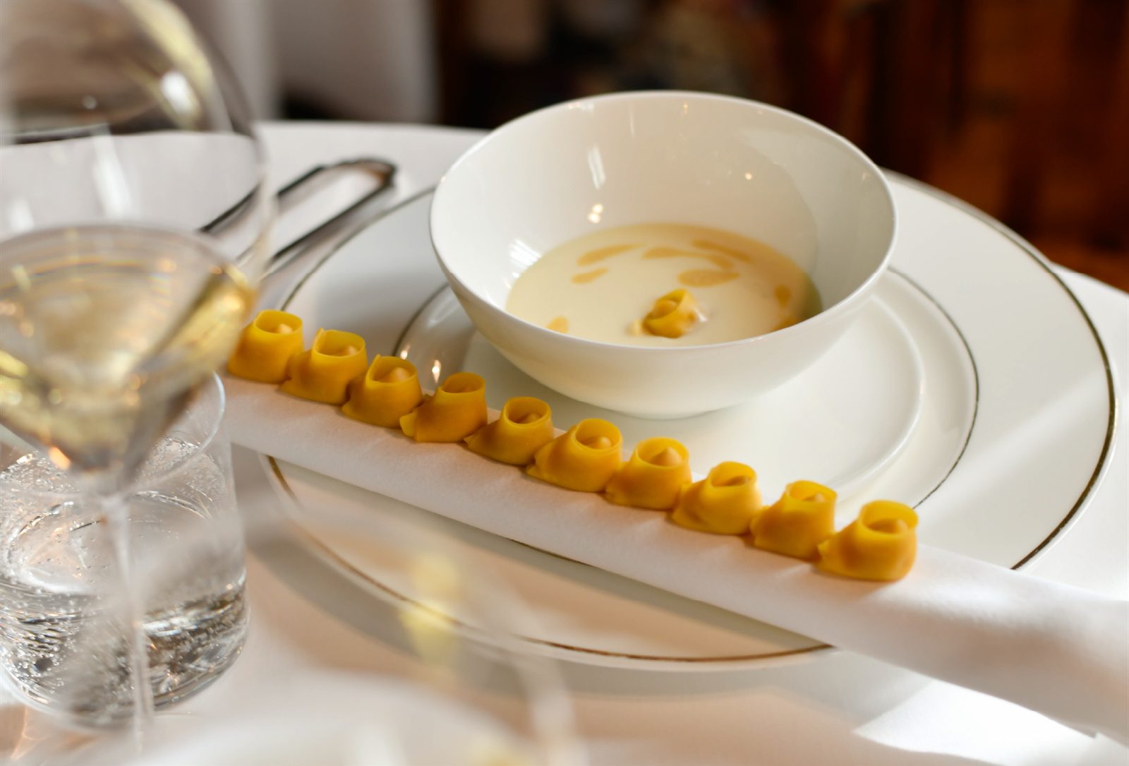 Tortellini in fila su piatto bianco con brodo — I nuovi classici