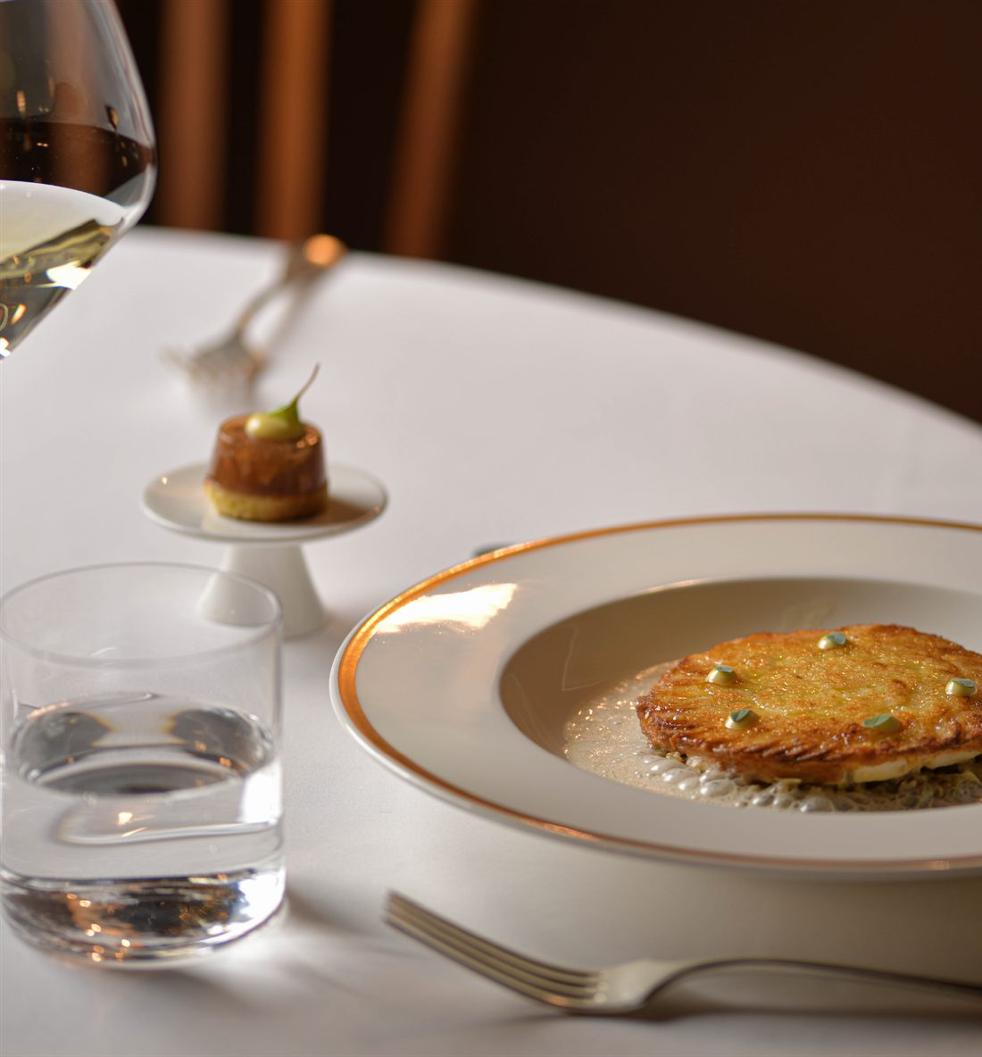 Tavola apparecchiata con un piatto della Brughiera, calice di vino e piccolo appetizer