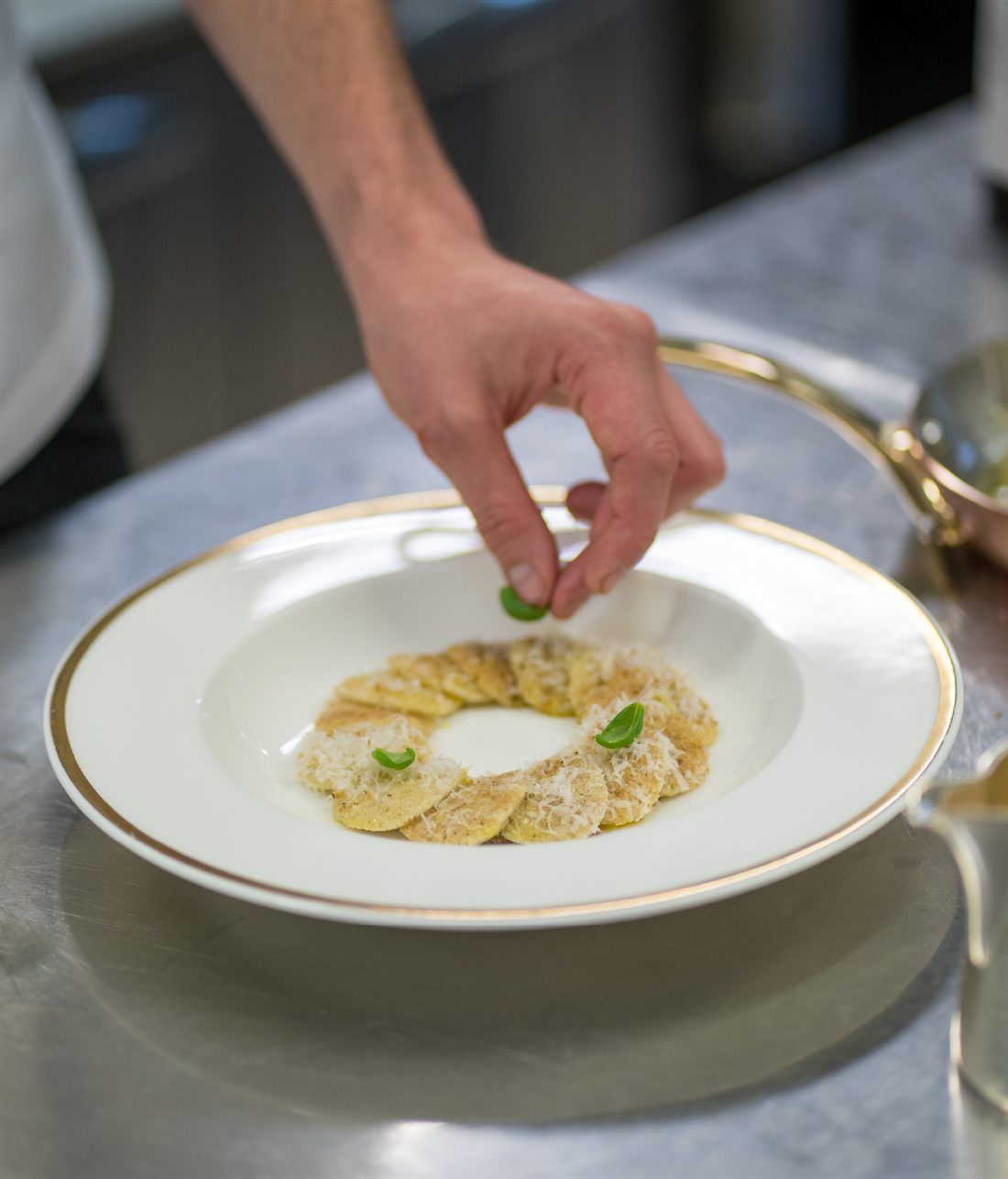Impiattamento in cucina: una mano completa un piatto con germogli freschi